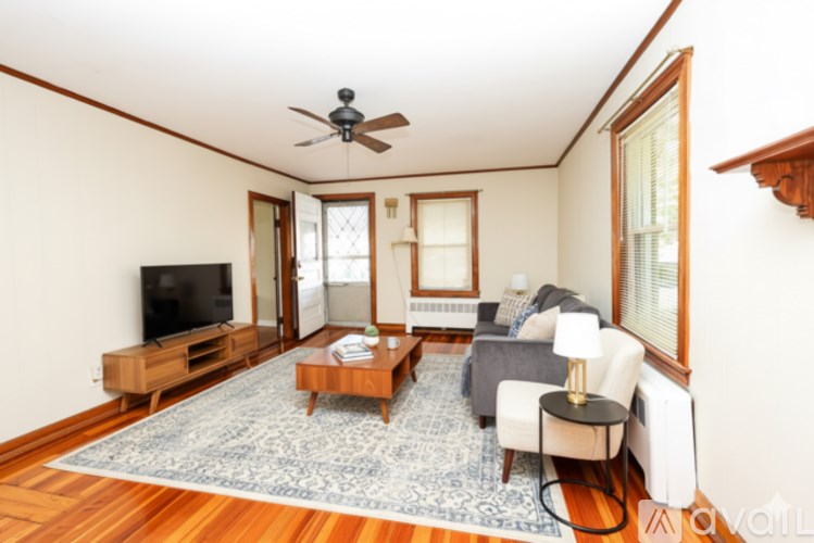 A living room with a television, a couch, a chair, and a rug.
