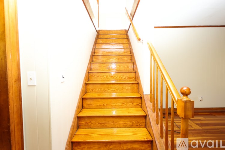 A wooden staircase with a banister on the right side.