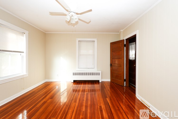 A room with a ceiling fan and wooden floors.