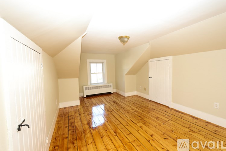 A room with wooden floors and a window with a radiator beneath it.