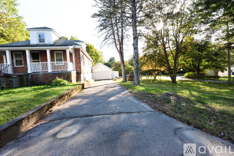 A residential street with a house on the left and trees on the right.