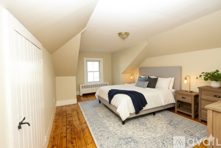 A bedroom with a bed, nightstand, and window.