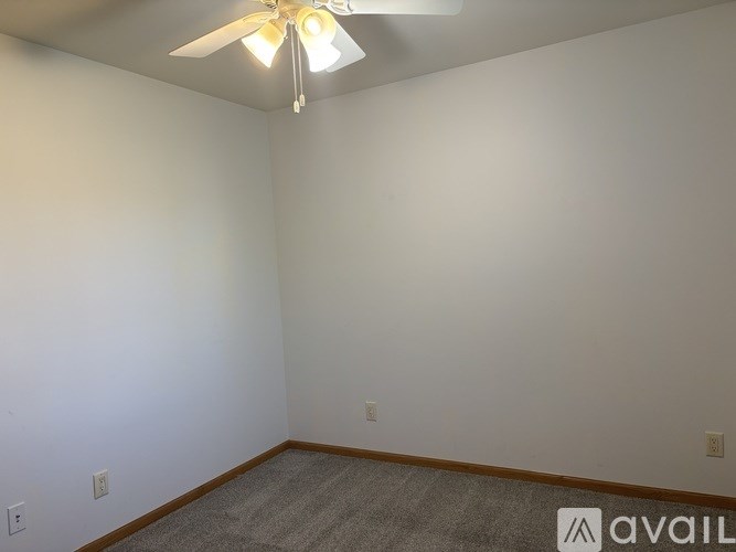 A room with a ceiling fan and carpeted floor.