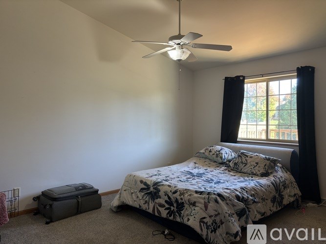 A bedroom with a bed, a ceiling fan, and a suitcase.