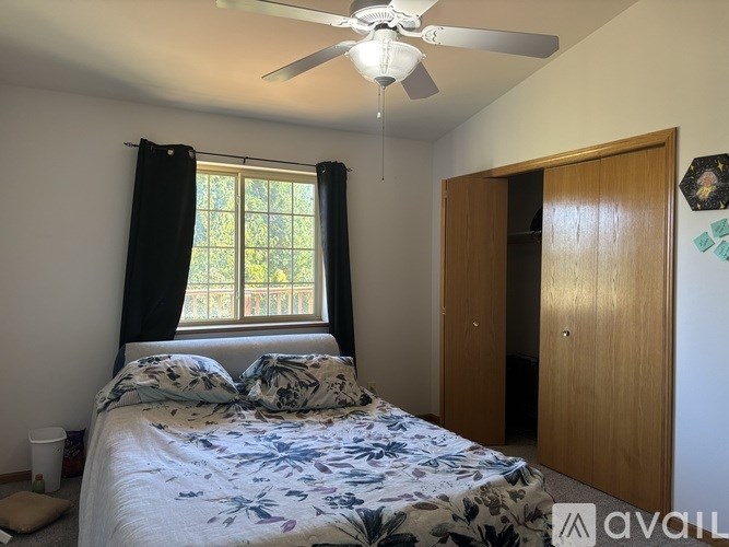 A bedroom with a bed, a ceiling fan, and a window with curtains.