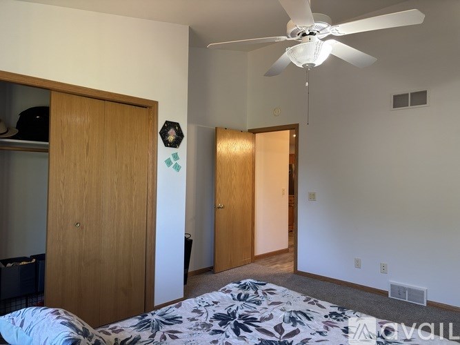 A bedroom with a bed, a ceiling fan, and a door with a window.