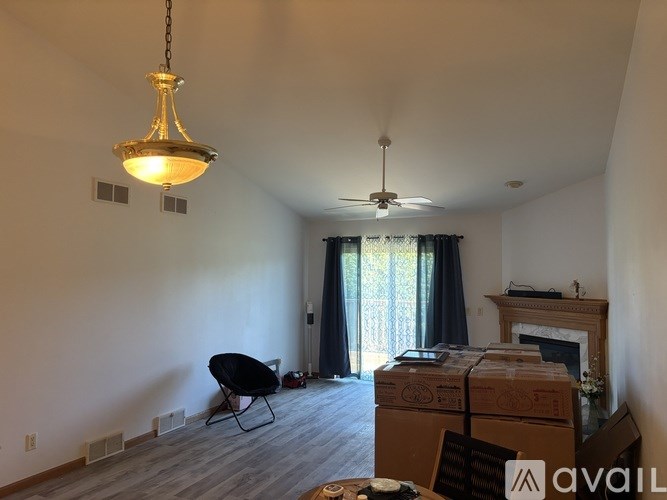 A room with a fireplace, a chair, and boxes on the floor.