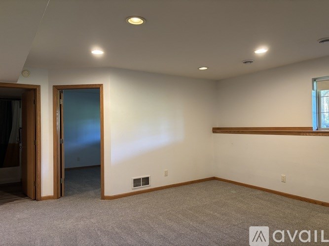 A room with a carpeted floor, a window, and a door.