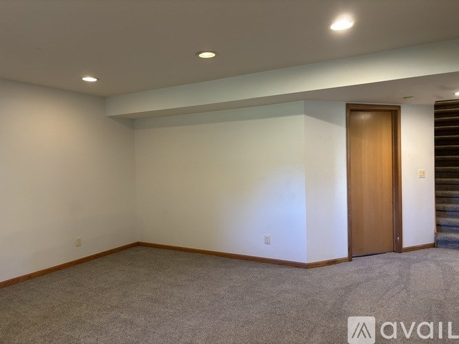 A room with a carpeted floor and a wooden door.