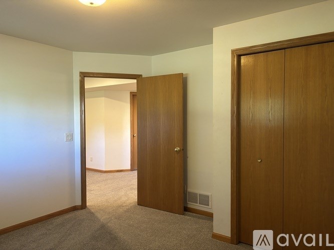 A room with a carpeted floor, two wooden doors, and a wall socket.