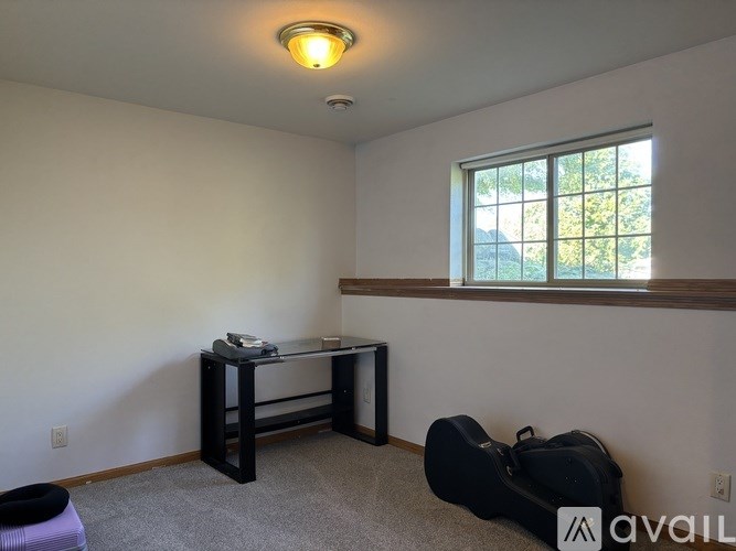 A room with a desk, chair, and a guitar case.