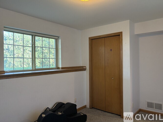 A room with a window, a door, and a suitcase on the floor.