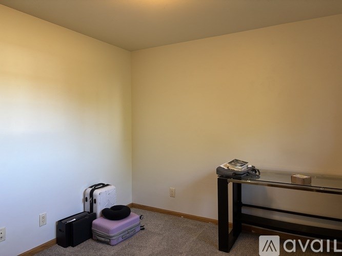 A room with a suitcase, a bag, and a table with a phone on it.