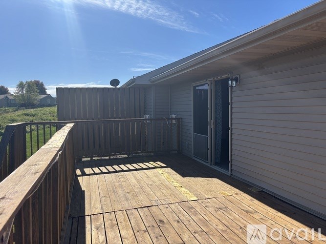 A deck with a railing and a sliding glass door leading to a patio.