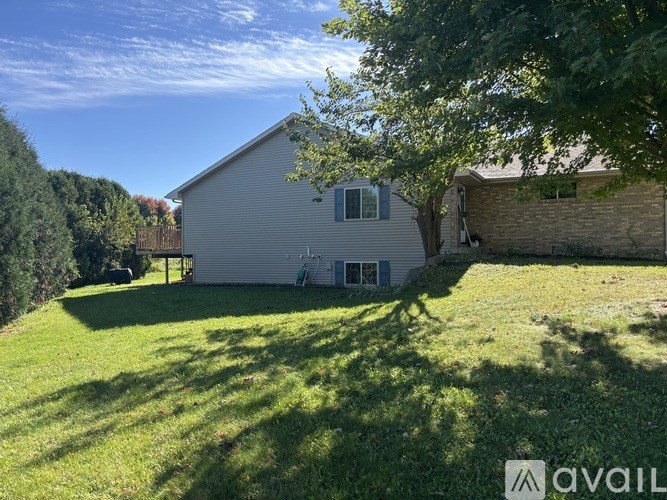 A house with a large lawn and trees in the background.