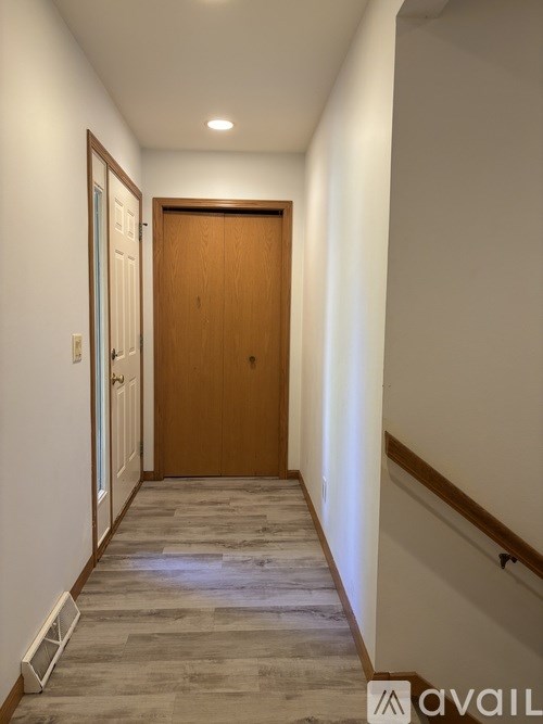 A hallway with a wooden door and a tiled floor.