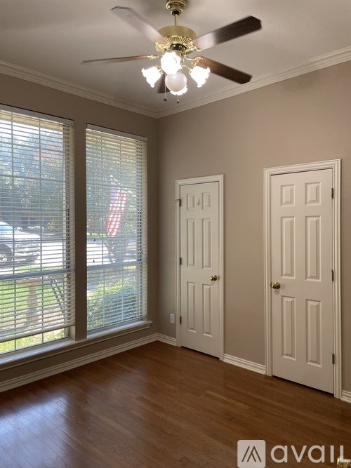 A room with a ceiling fan and two doors.