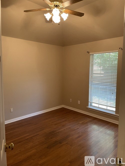 A room with a ceiling fan and a window with blinds.