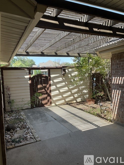A patio area with a wooden pergola and a stone pathway.