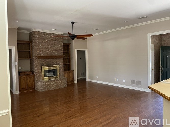 A spacious living room with a fireplace and a ceiling fan.