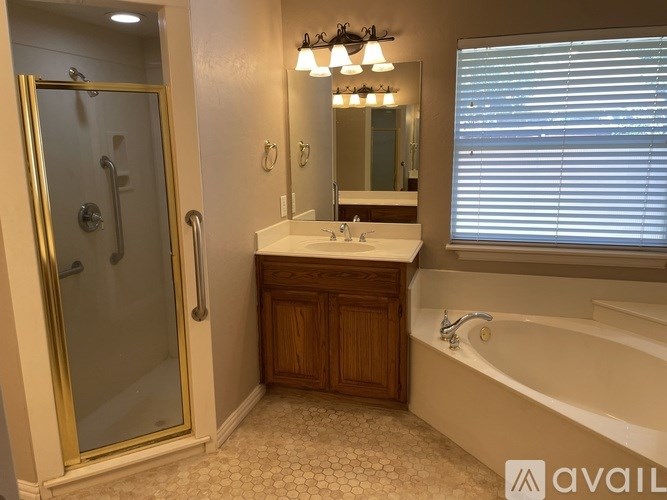 A bathroom with a glass shower door, a wooden cabinet, and a bathtub.