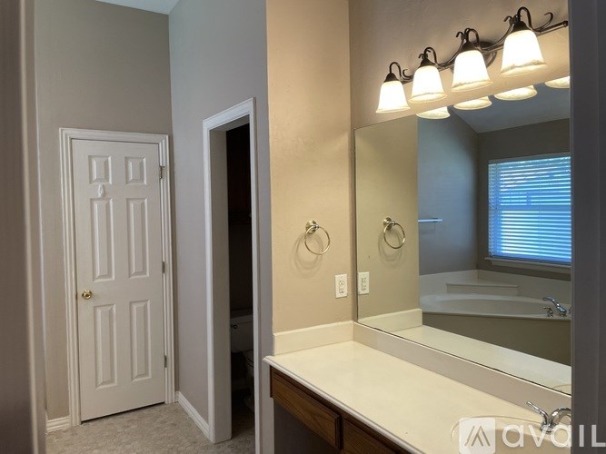 A bathroom with a white door, a mirror, and lights above it.