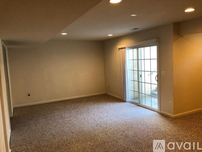 A carpeted room with a sliding glass door leading outside.
