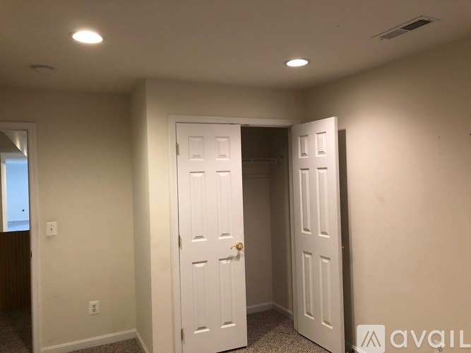 A room with two white doors and a window on the left.