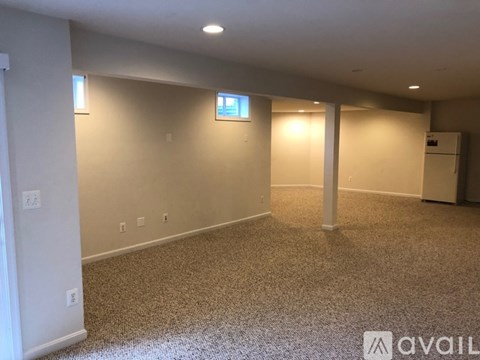 A spacious room with a carpeted floor and a small TV mounted on the wall.