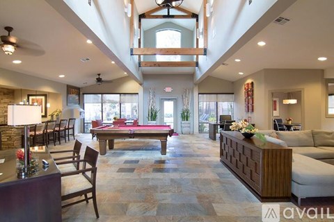 A spacious living room with a pool table and a bar area.