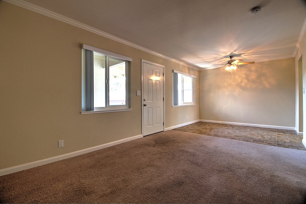 an empty living room with a ceiling fan