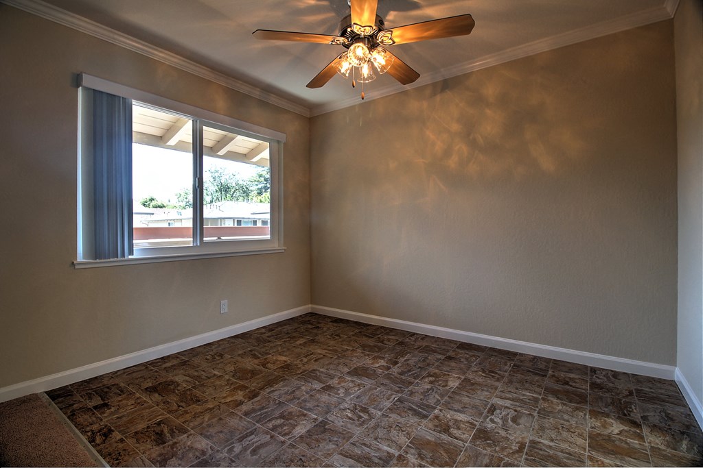 an empty living room with a ceiling fan and a window