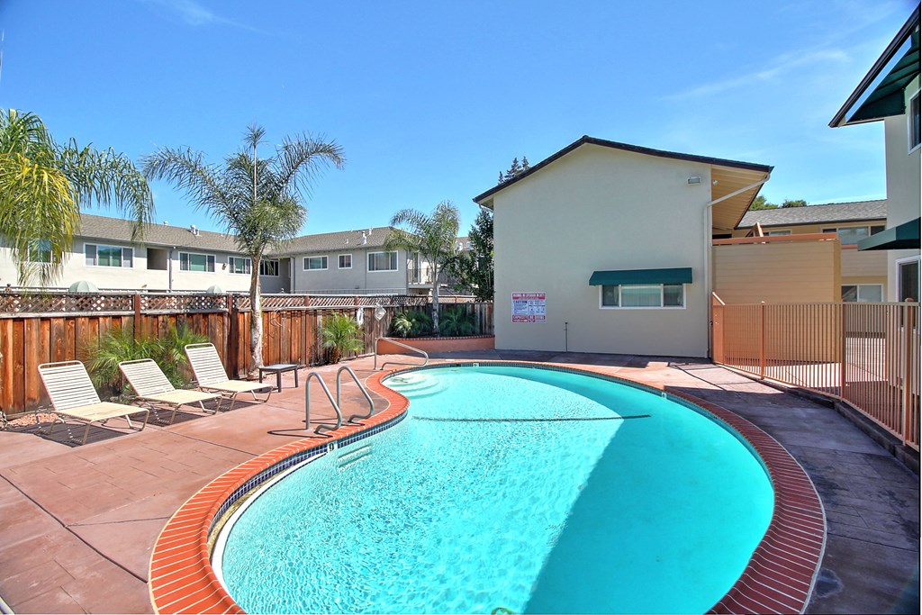 a swimming pool with chairs and a house in the background
