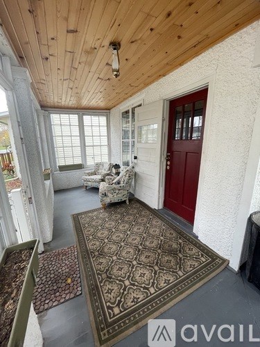 A living room with a red door and a rug on the floor.