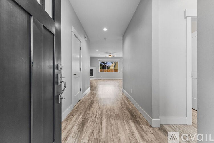 A long hallway with a wooden floor and a black door on the left.