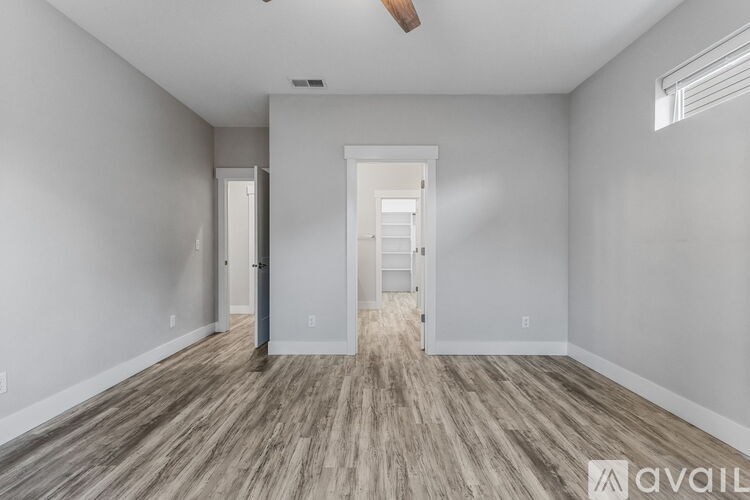 A spacious room with wooden flooring and white walls.