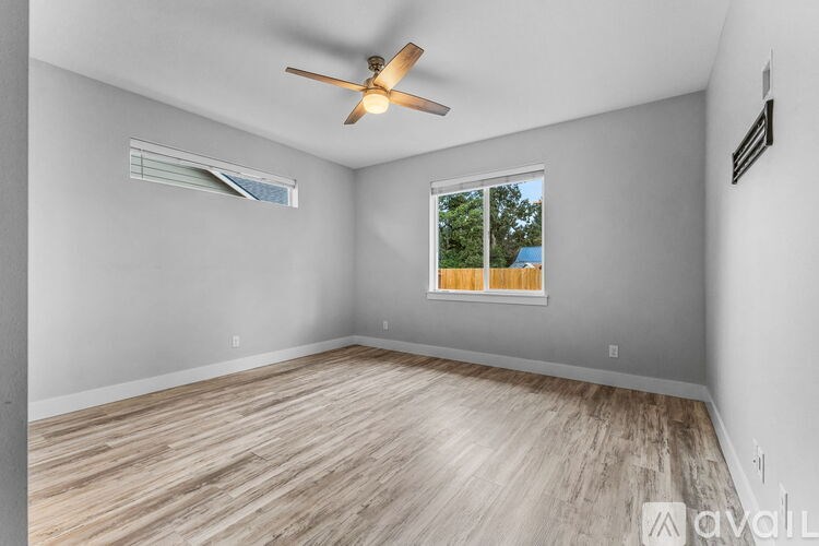 A room with a ceiling fan and a window showing greenery outside.