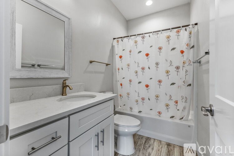 A bathroom with a floral shower curtain and a marble countertop.