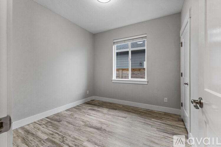A room with a window and wooden flooring.