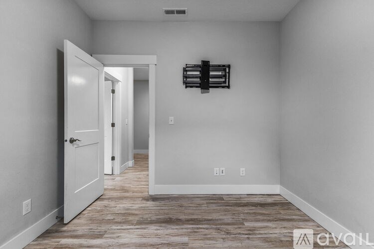 A room with a white door and a white wall with a black shelf above it.