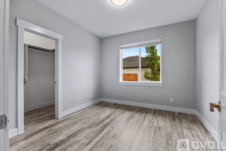 A room with a window showing a view of a house and trees.