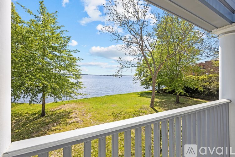 A balcony overlooks a grassy area and a body of water.