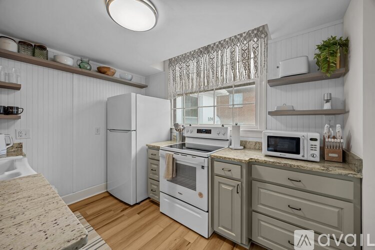 A kitchen with white appliances and wooden floors.