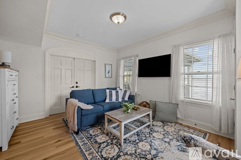 A living room with a blue sofa and a television on the wall.