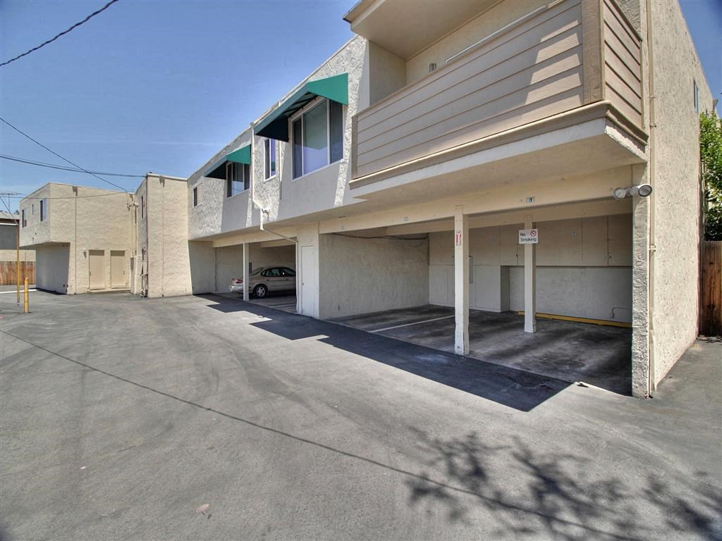 A parking lot in front of a building with a car parked.