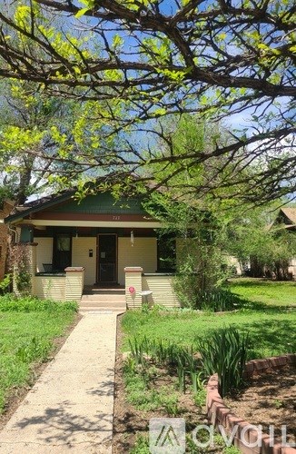 A house with a green lawn and a tree with yellow leaves in front.