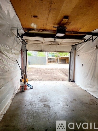 A room with a white tarp on the walls and a broom leaning against the wall.