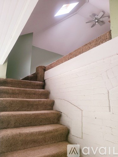 A staircase with a carpeted runner and a white brick wall.