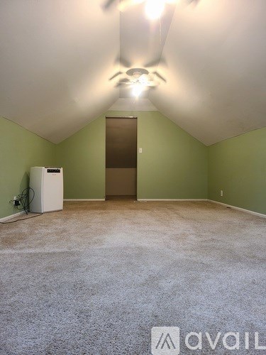 A room with a carpeted floor and a ceiling fan.