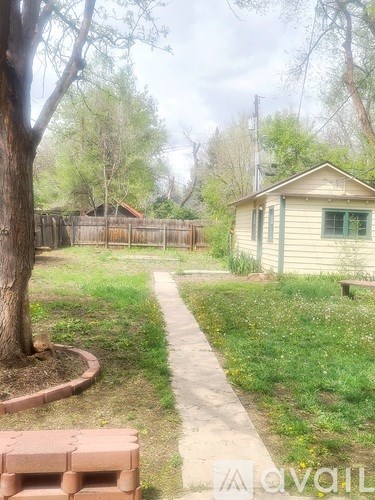 A backyard with a small house, a tree, and a brick wall.